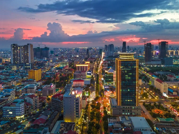 Aerial dusk view of Phnom Penh's skyline with the illuminated Canadia Tower standing out among surrounding buildings