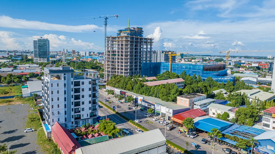 Elevated view over Chroy Changvar's boulevard with a high-rise tower under construction and roadside shops
