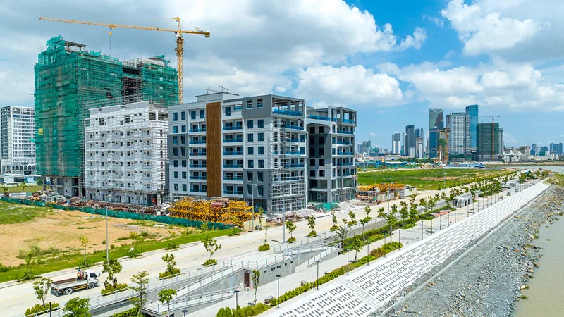 Norea City under construction — scaffolded mid-rise buildings and tower cranes beside the newly built riverside embankment promenade