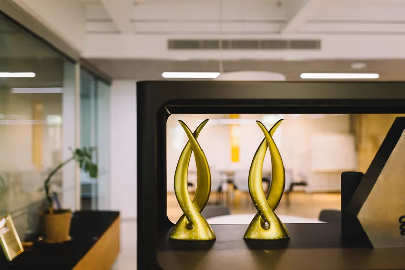 Reception detail at Raintree with two International Property Award trophies and an open workspace behind