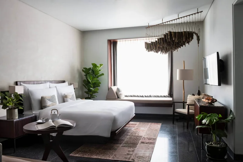 Treeline Urban Resort guest room with driftwood mobile, window seat and contemporary Khmer furnishings